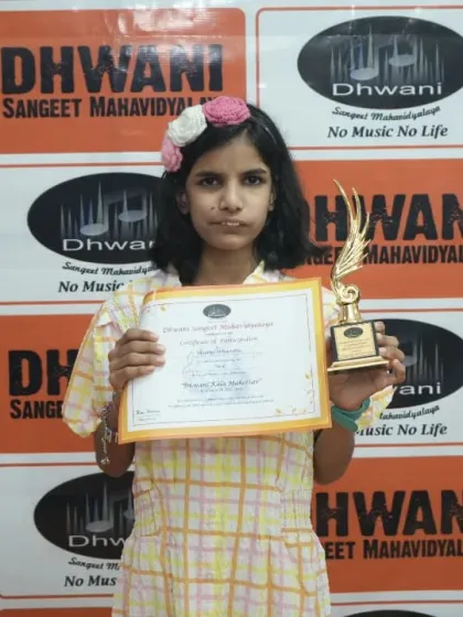 A student proudly holds her certificate and trophy.