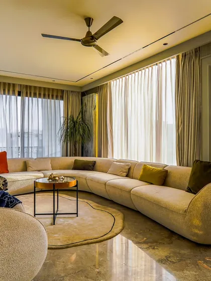 The large curved sofa is the centerpiece of this comfortable living room. It’s an inviting piece of furniture that defines the room's soft, organic feel, perfect for family gatherings.