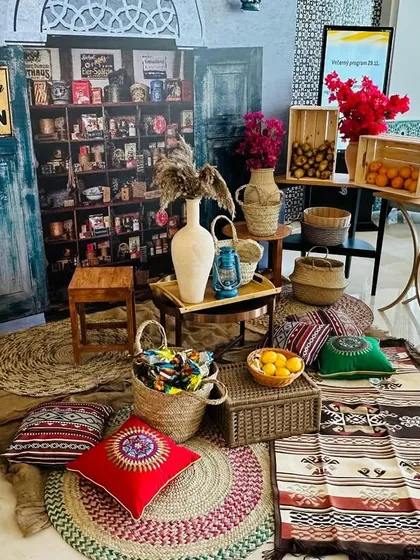 A charming and rustic decor corner for a welcome lunch in Doha. The setup includes traditional rugs, cushions, and local snacks, creating a warm and inviting atmosphere.