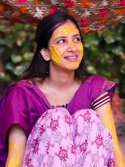 A candid moment of the bride looking up with a smile during her Haldi ceremony. The warm colours and her relaxed expression make this a beautiful, natural portrait.