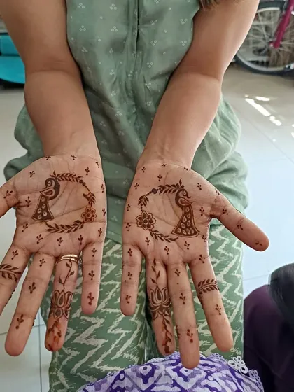 A minimalist peacock design within a leafy circle on the palm. This is a simple and artistic way to incorporate traditional motifs.