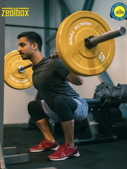 The weighted back squat is a fundamental movement for building overall strength. Here, a member demonstrates proper form, engaging his quads, glutes, and core under a heavy load.