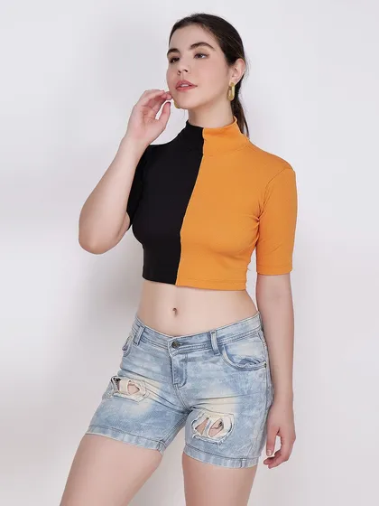 A standard three-quarter shot of a model in a two-toned crop top and denim shorts, a staple for any e-commerce platform.