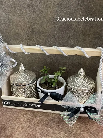 A perfect hamper for a silver jubilee celebration. This wooden tray is decorated in a silver and black theme and includes two silver crystal jars and a central planter. It's fully customizable and under ₹1000.