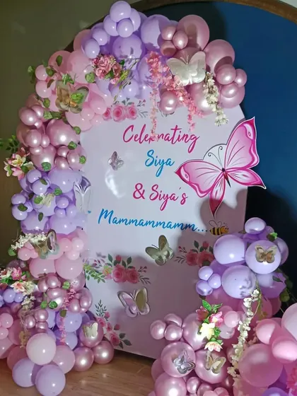 A beautiful butterfly-themed celebration with a custom arched backdrop and a lush balloon garland in shades of pink and purple.