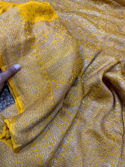 A closer look at the rich texture and weaving of the yellow Banarasi silk saree. The antique gold zari work is dense and luxurious.
