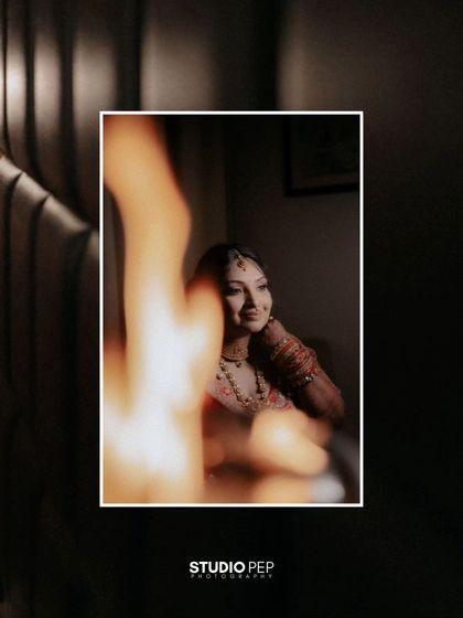 An artistic shot of Shalini, with a fire element blurred in the foreground, creating a warm and dramatic effect.