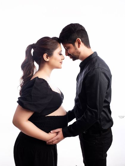 An intimate forehead-to-forehead pose that beautifully captures the connection between the couple. The all-black outfits create a modern and sophisticated look against the clean white studio background.
