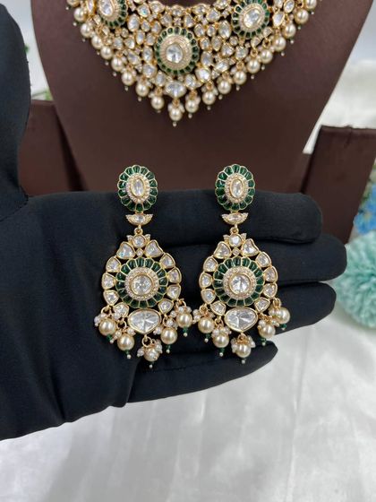 The Zarista Premium Moissanite Necklace set, shown here in both ruby and green variations. This set includes a necklace, maang tikka, and earrings, featuring large central stones surrounded by detailed craftsmanship.