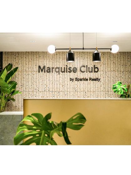 The reception desk is set against a wall of custom terrazzo tiles. The modern pendant light and lush greenery create a sophisticated and inviting first impression.