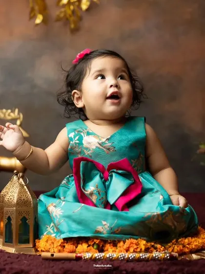 A festive-themed sitter session. This baby girl looks adorable in traditional wear, surrounded by marigolds and lanterns.