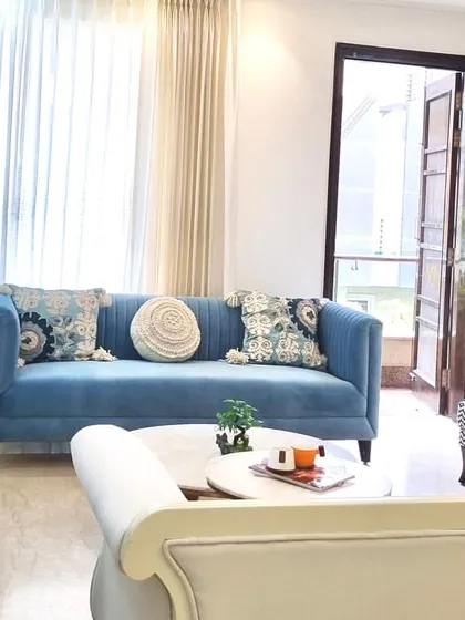 Natural light floods this living room through the large doors, enhancing the fresh and airy feel of the blue and white color scheme. The patterned wingback chair adds another layer of style.