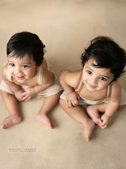 Ten-month-old twin brothers looking up with sweet, curious expressions. Photographing them together at this age is a beautiful way to document their journey.
