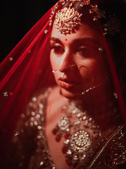 A striking close-up of the bride, with the red veil creating a powerful and intense mood.