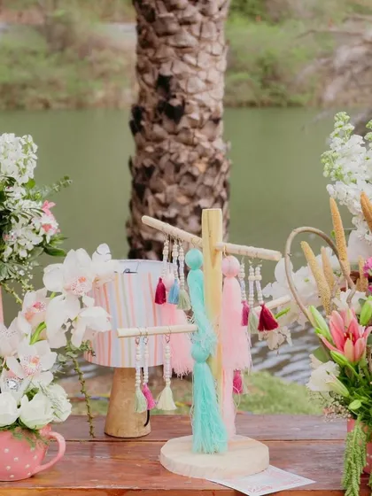 A close-up of the vibrant details from our 'Sunny Sway Soirée', including lush floral arrangements in polka-dot mugs and a colorful tassel tree.