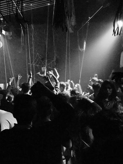 Another monochrome shot of the Belgaum crowd, with skeletons from the Halloween decor hanging above. It creates a moody, underground atmosphere.