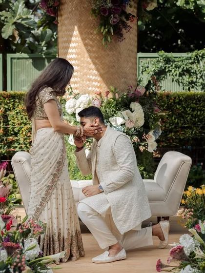 A tender moment as the groom kisses the bride's hand, framed by the beautiful, sustainable decor we created.
