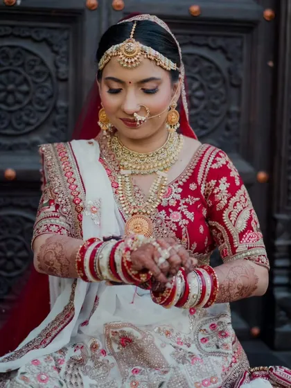 A quiet moment as the bride adjusts her bangles. This shot highlights the harmony between her makeup, her intricate henna, and her stunning jewelry, all coming together to create a complete bridal look.