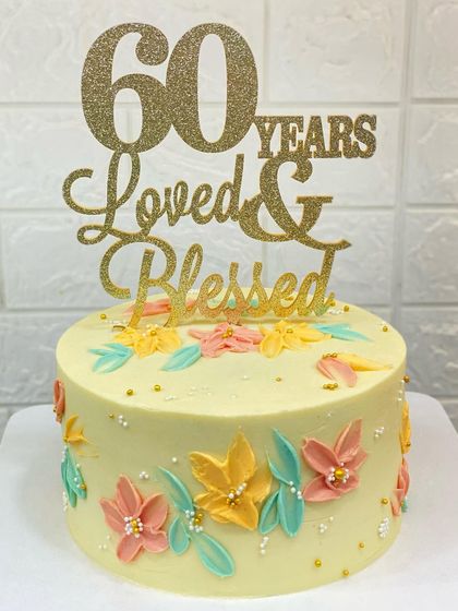 A beautiful cake for a 60th birthday, featuring delicate, hand-painted flowers made with a palette knife technique. The message "60 Years Loved & Blessed" says it all.