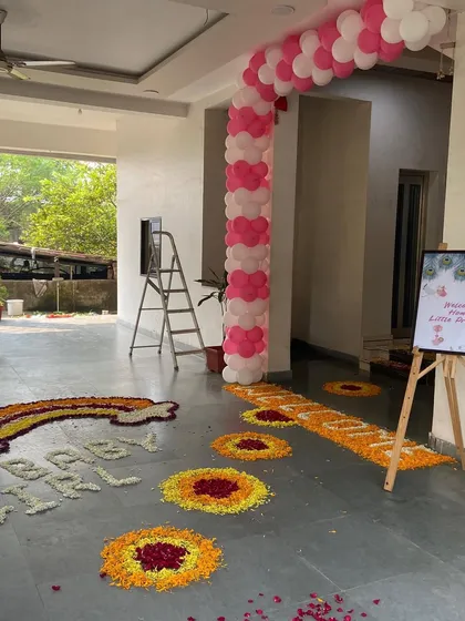 A beautiful flower rangoli design on the floor for a 'Welcome Home Little Princess' event, including a rainbow and footprint patterns.