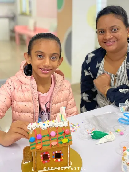 A mother and daughter team up to create a beautiful gingerbread house, complete with marshmallow decorations.