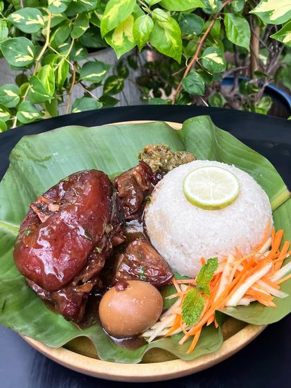Another look at our Sweet Pork Knuckles combo, beautifully plated on a banana leaf. The glistening, sweet glaze on the pork is perfectly balanced by the sticky rice and tangy chutney.