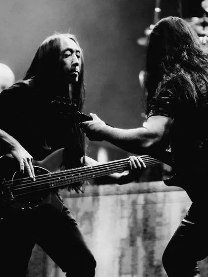 A black and white shot capturing the intricate musicianship of Dream Theater's John Myung and John Petrucci interacting on stage.