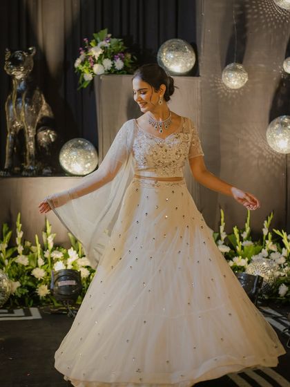 A joyful pose in the same white lehenga, capturing the fun and festive spirit of a wedding celebration.