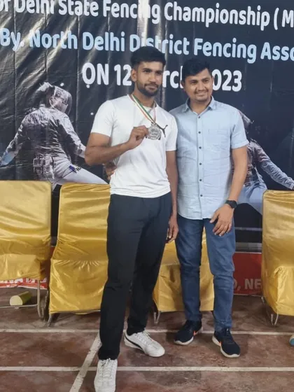 A senior medalist from the Delhi State Fencing Championship, celebrating his victory with his coach.