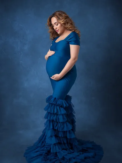 A beautiful side profile, showcasing the dramatic mermaid silhouette of the gown and her baby bump.