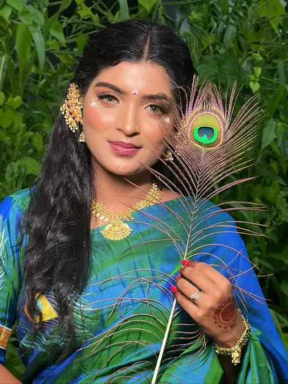 A smiling portrait of the model in the peacock-themed saree, her makeup looking fresh and radiant.