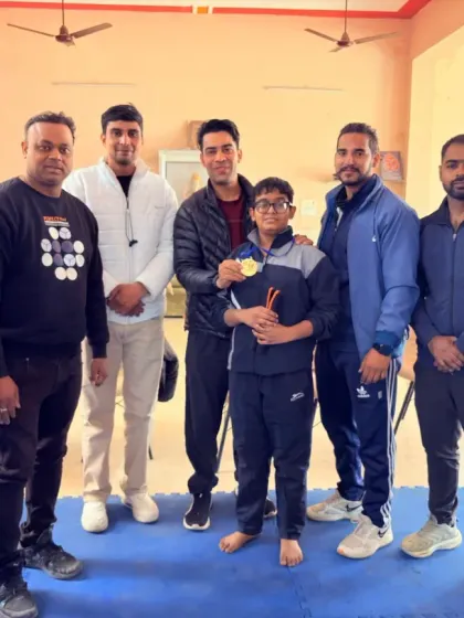 Another proud student with his gold medal, surrounded by his coaches and mentors. We celebrate every victory together.