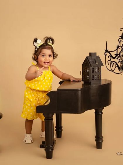 Pointing to her next masterpiece. This little musician is full of personality in her yellow polka-dot outfit, interacting with the camera during her piano-themed session.