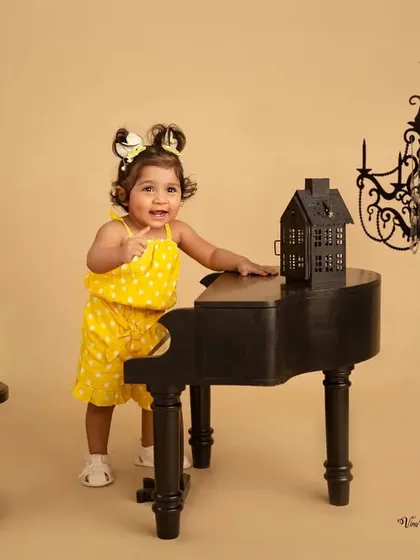 Pointing to her next masterpiece. This little musician is full of personality in her yellow polka-dot outfit, interacting with the camera during her piano-themed session.
