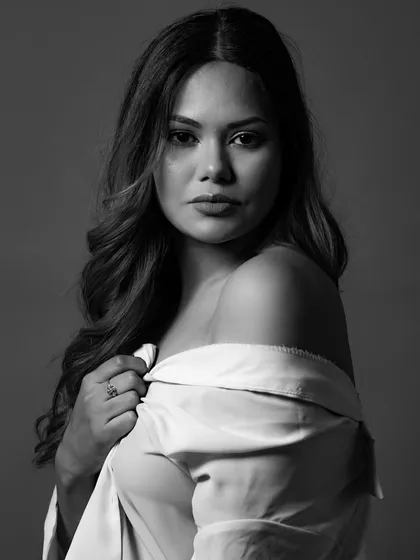 A classic black and white portrait with the model wearing an off-shoulder white shirt. The simple styling and soft lighting create a timeless and elegant image that focuses on natural beauty.