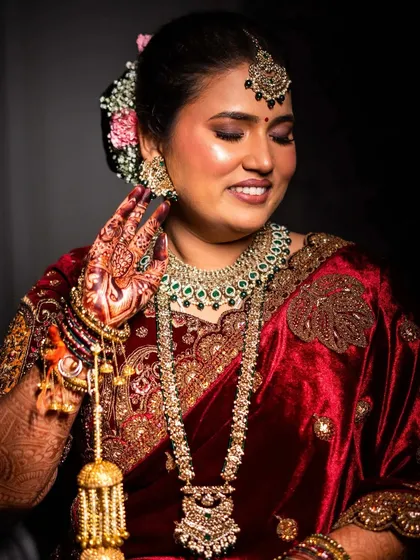 A close-up of the bride, showing off her intricate kalire and beautiful floral bun. Her glowing skin and happy smile complete the look.