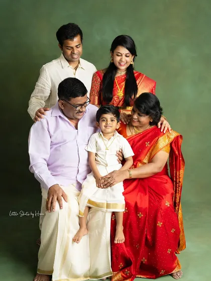A wonderful multi-generational family portrait. The grandparents, parents, and grandchild are all together, dressed in traditional attire, capturing the love that spans across generations.
