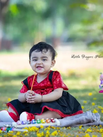 Such a happy smile from the birthday girl. This first birthday portrait captures her joy as she plays with a toy xylophone in a field of yellow flowers.