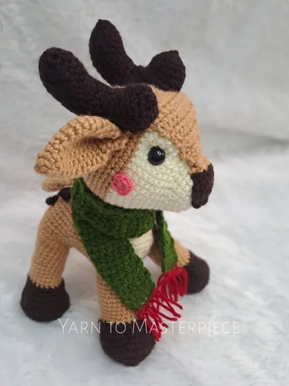 My crochet reindeer soft toy is perfect for Christmas decor. He has a festive green and red scarf and cute little antlers.