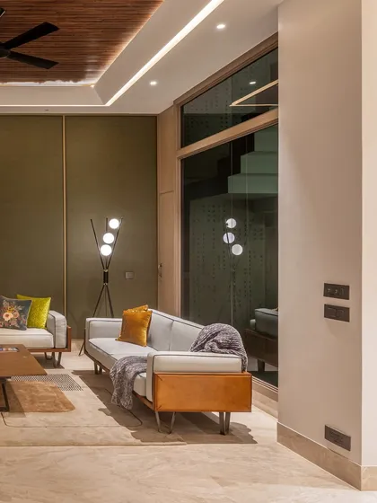 The reflection in the glass shows how the lounge is connected to the rest of the home, with a staircase visible in the background. This visual connection enhances the sense of space and flow.