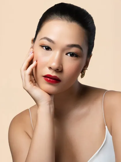 A classic beauty portrait. The soft lighting enhances the glowing skin, while the bold red lip and winged liner provide a touch of timeless Hollywood glamour.