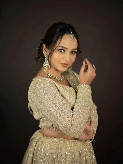 A smiling portrait of the model in the golden-beige lehenga.