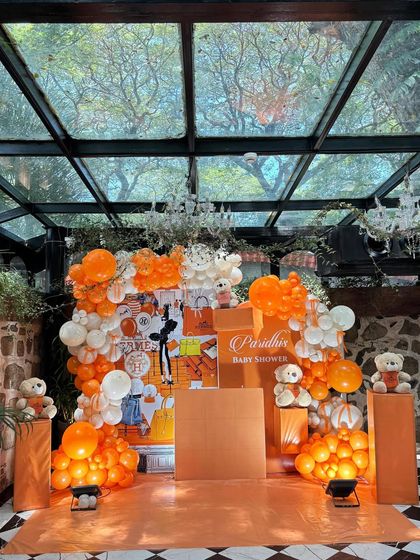 The full decor setup for the Hermès-inspired baby shower, set in a beautiful glasshouse venue that enhanced the vibrant orange and white color scheme.