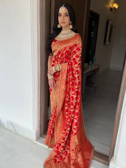 A full-length view of the bride in her royal red saree, with her hair in classic, flowing waves.