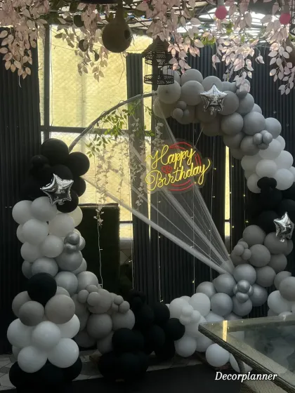 This shot captures the full half-ring design of the balloon arch, a popular and modern choice for birthday backdrops. The monochrome palette is timeless and elegant.