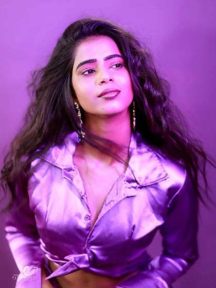 A thoughtful and serene expression against a vibrant purple backdrop. The soft lighting complements the sheen of the satin.