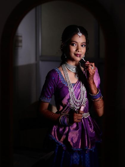 A 'getting ready' shot of a woman applying lipstick. These behind-the-scenes moments add a personal touch to the story of an event.