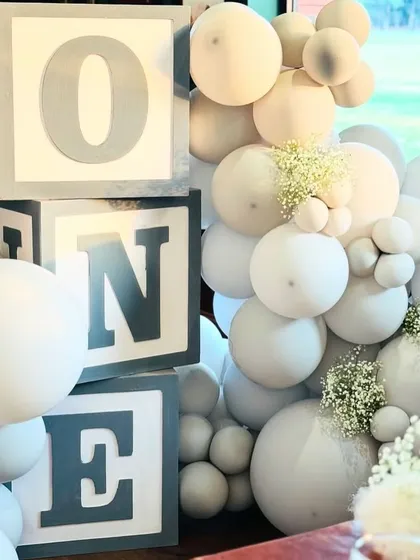 Giant 'ONE' letter blocks in a matching grey and white color scheme, nestled among the balloon decor, are perfect for first birthday photos.
