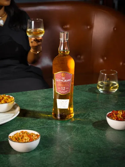 An on-location lifestyle shoot for a whisky brand's Diwali campaign. The setting is a sophisticated bar, with a model holding a glass to create a sense of occasion and luxury.