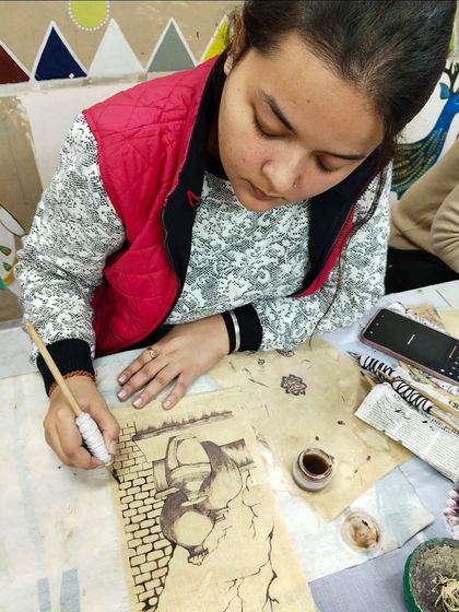 A student practicing Kalamkari painting, an ancient style of hand-painting that uses a tamarind pen and natural dyes.